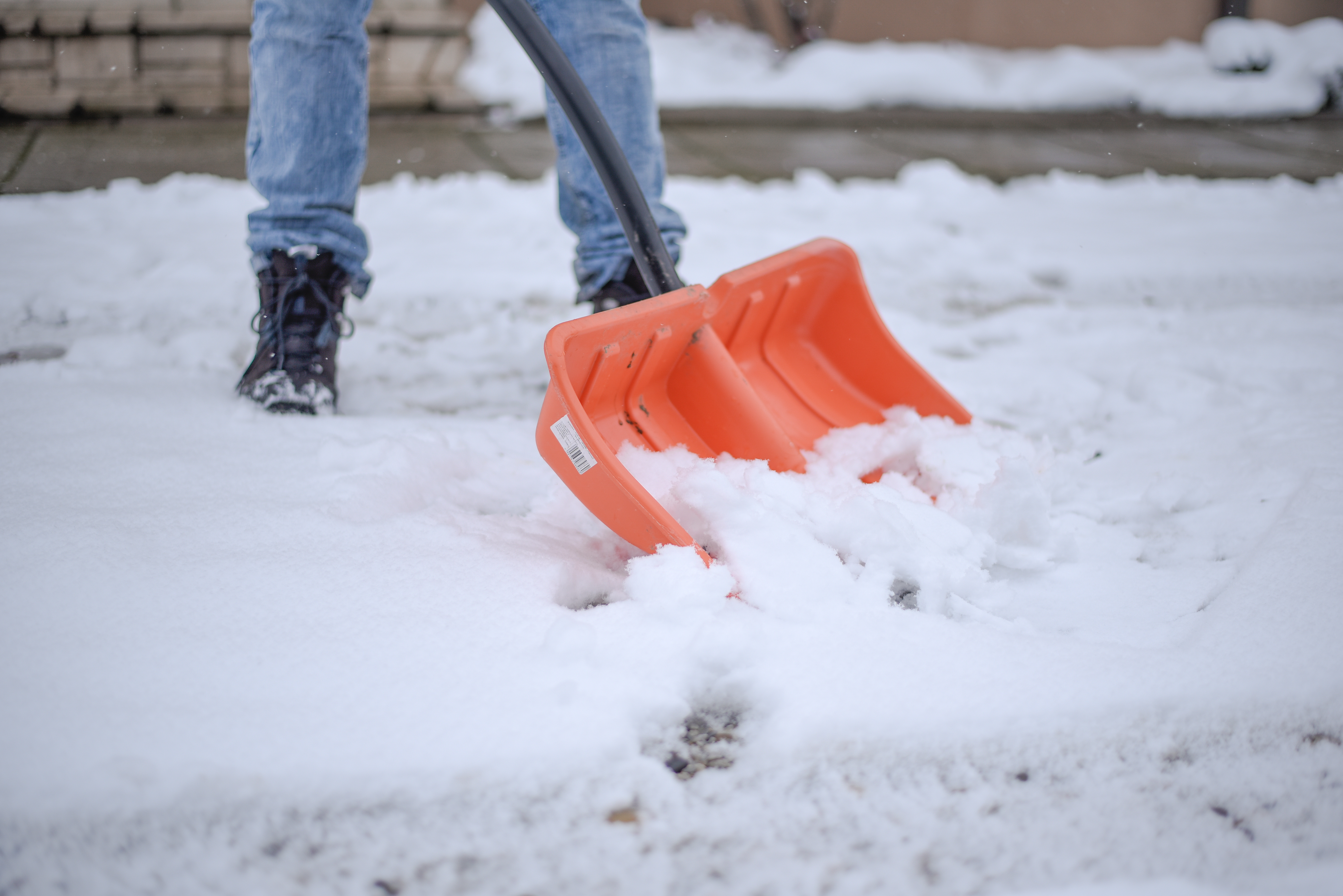 Public service worker or citizen cleaning the snow on the road with a shovel