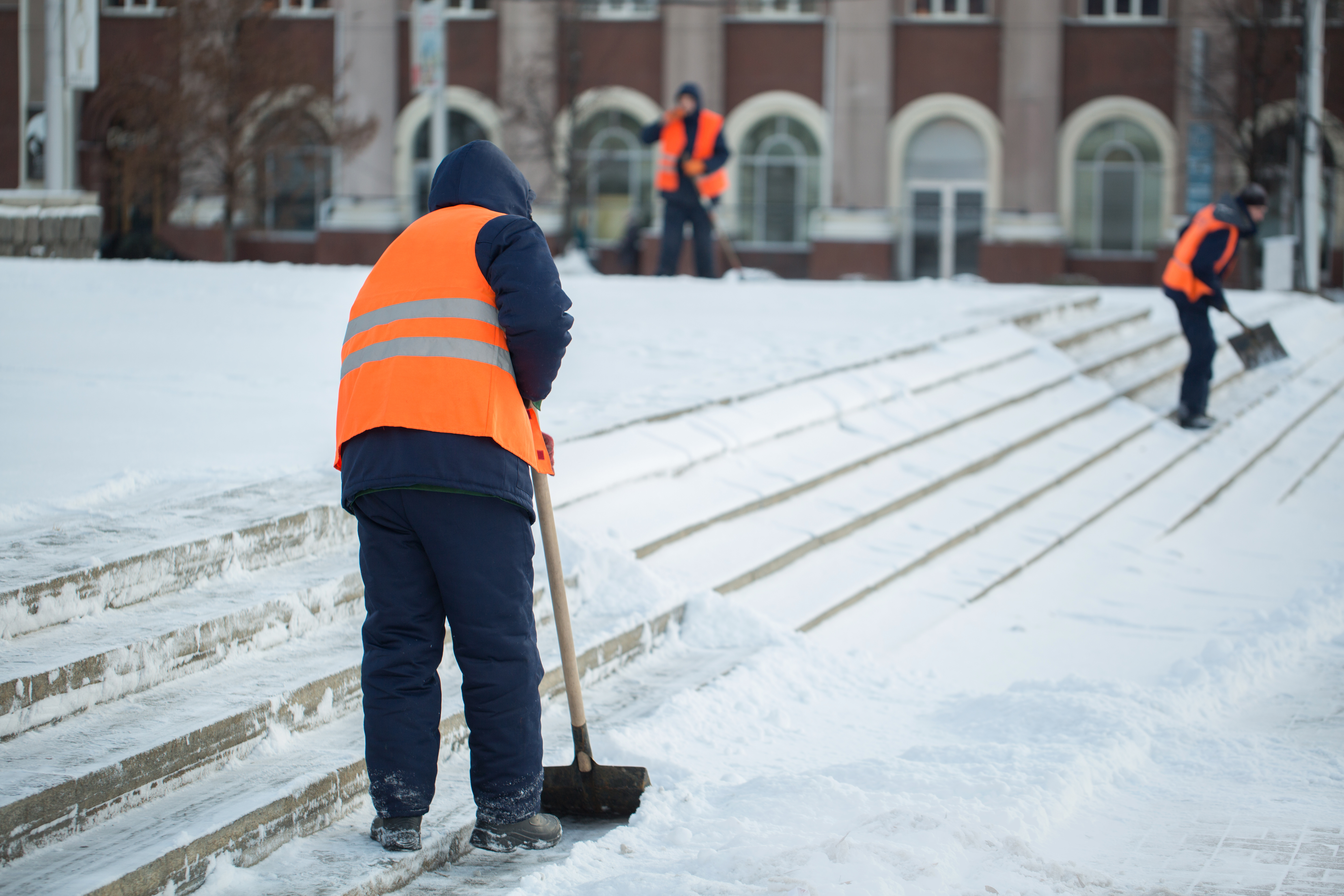 Workers sweep snow from road in winter, Cleaning road from snow storm.